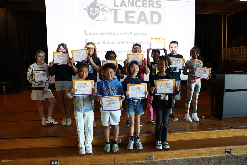 Students hold up their Lancers Lead certificates Purposefull and respectful