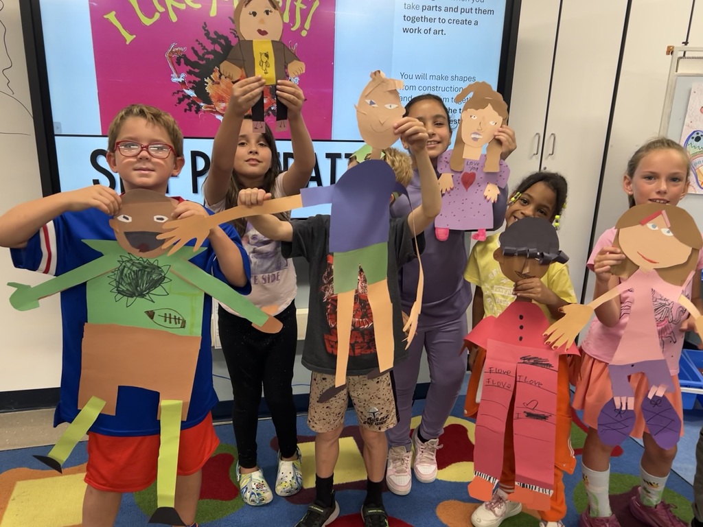 Students hold up art creations