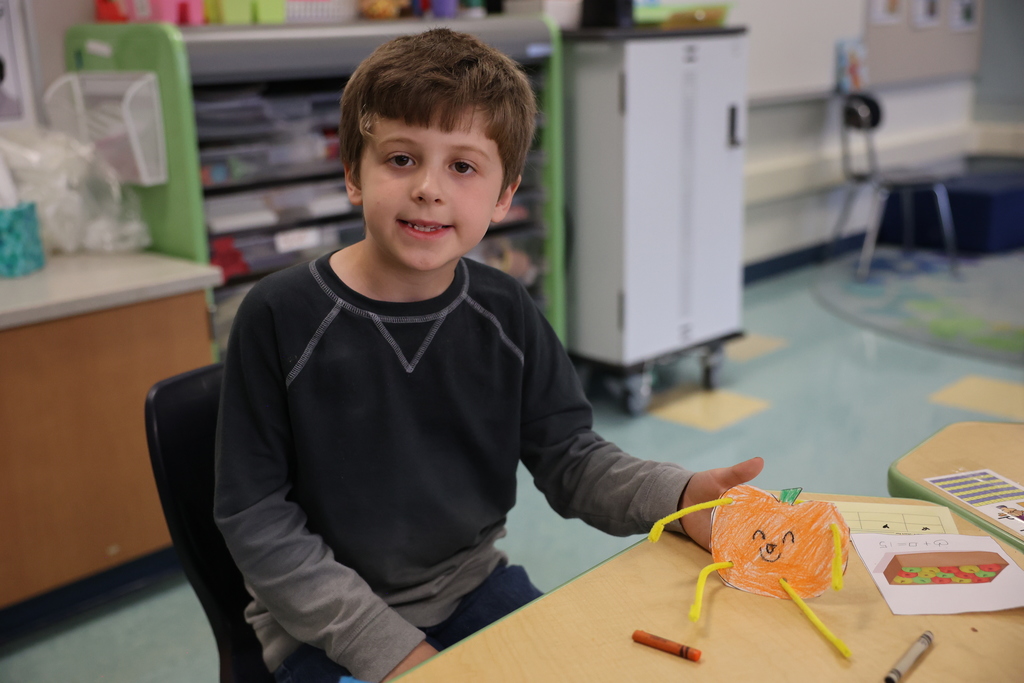 student holds up art and smiles