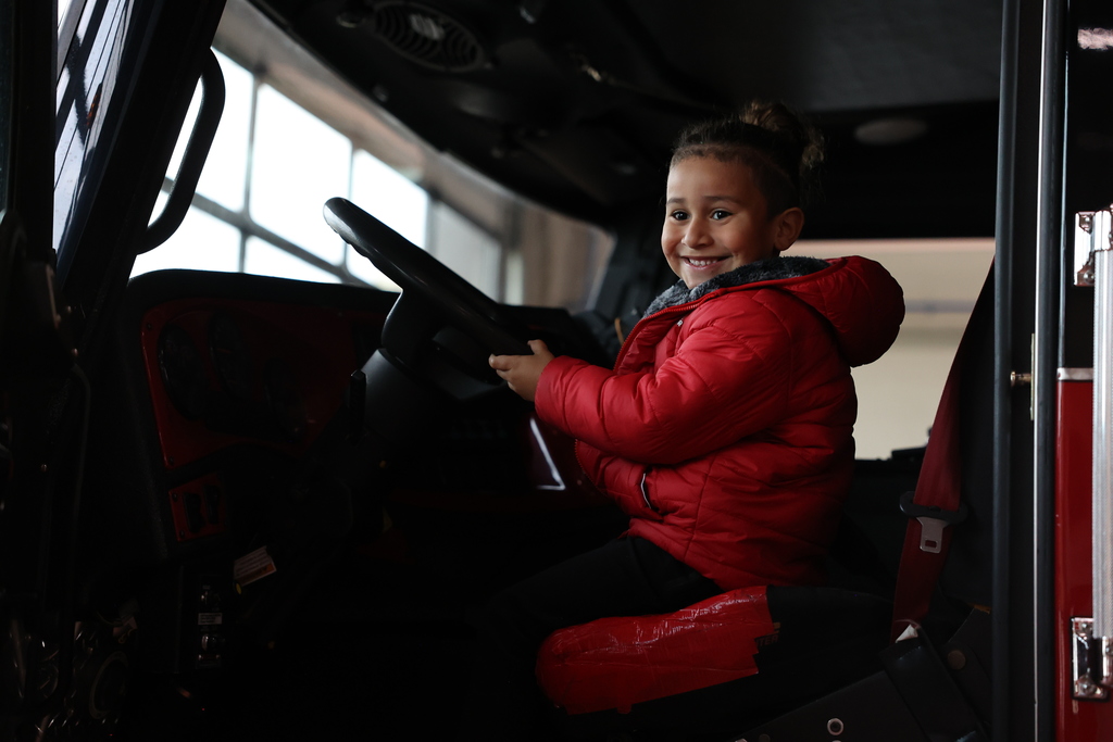 student smiles in firetruck at steering wheel