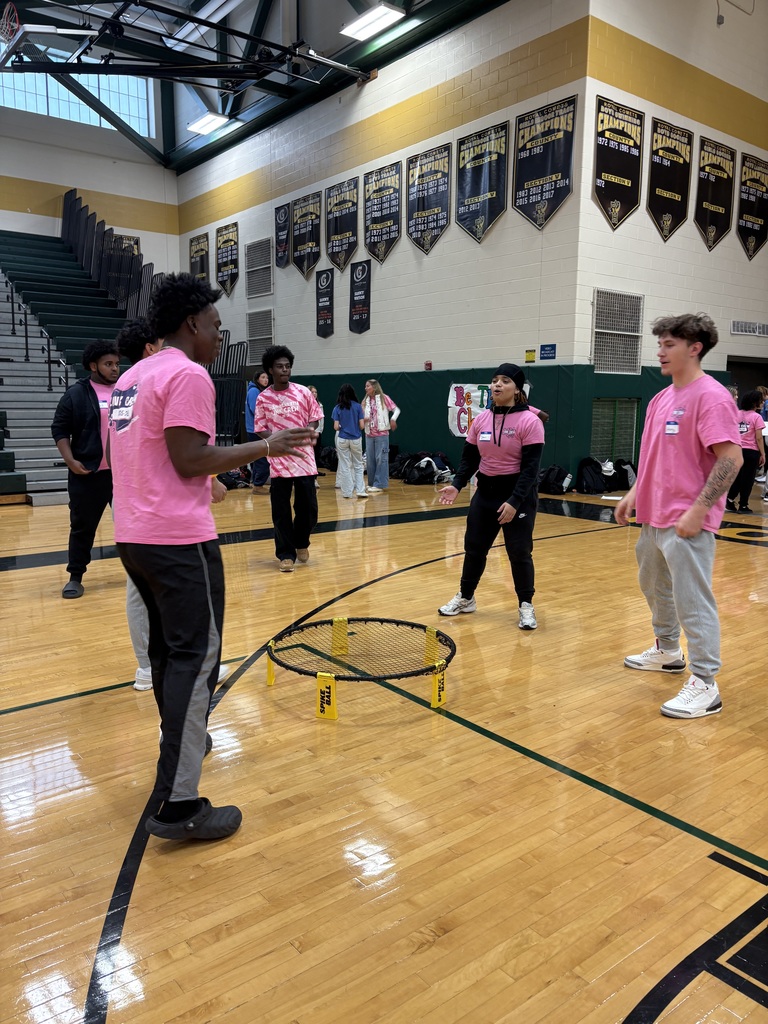 Students play game in the gymnasium with pink shirts on