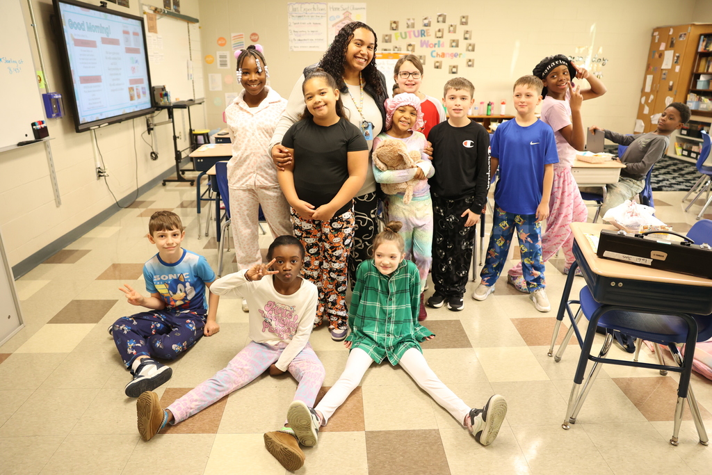 students pose with teacher in their pjs
