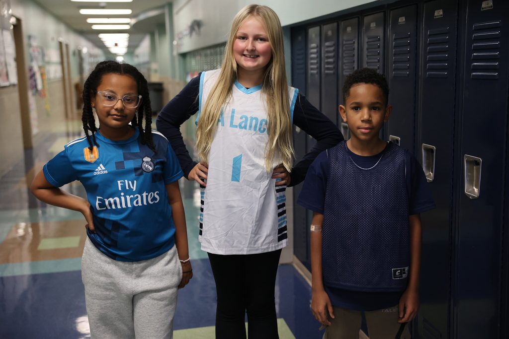 Three students pose in the hallway wearing jerseys