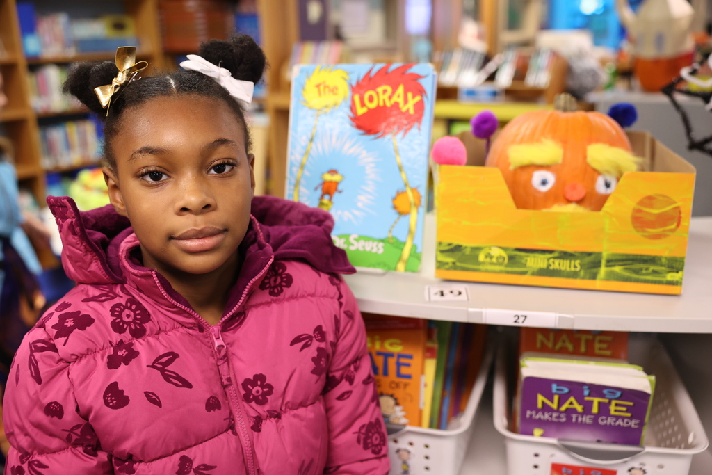 student poses with pumpkin creation