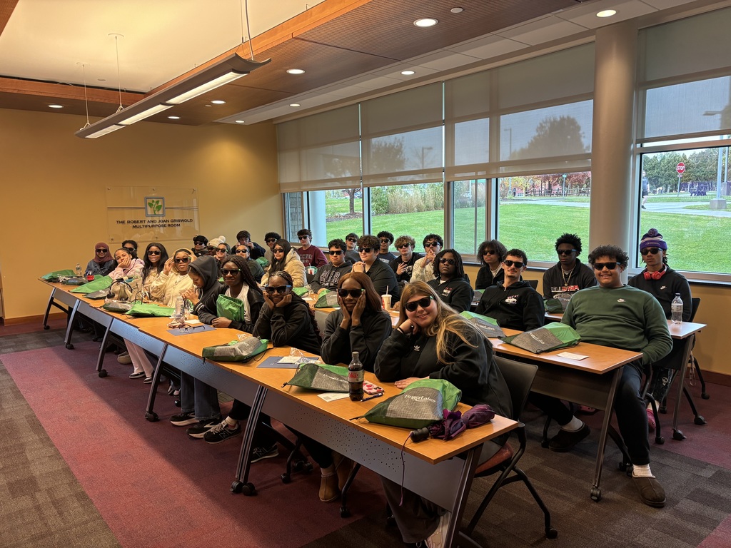 students pose in sunglasses at desks