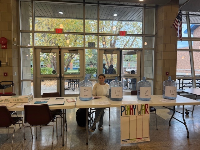 student stands behind table with collection jars
