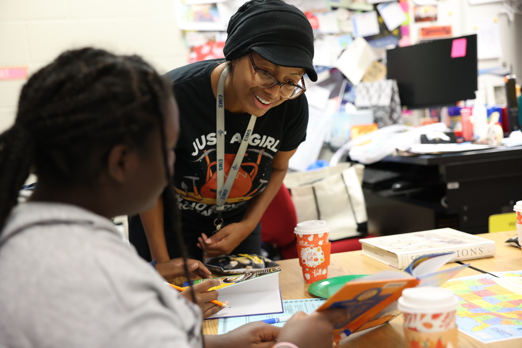 teacher looks at book with student