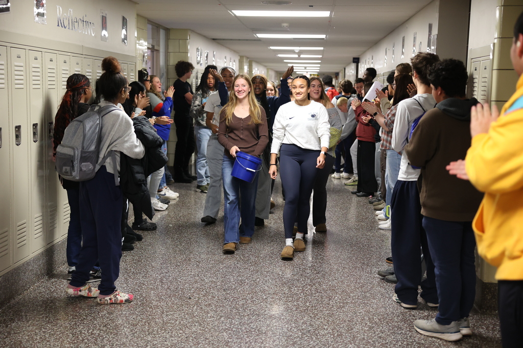 girls volleyball team walks through the hallways as fellow students cheer