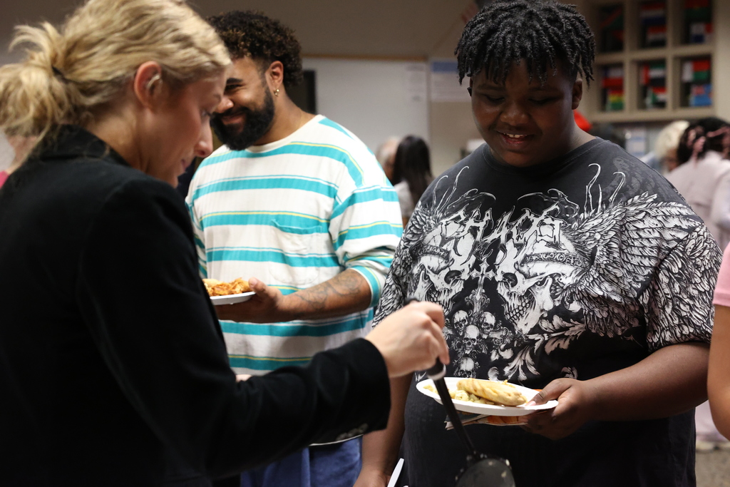 Student smiles while receiving food on plate