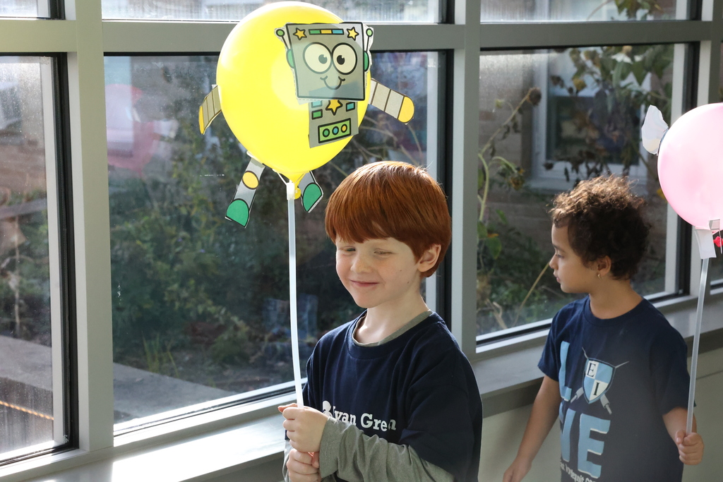 student holds up balloon and smiles