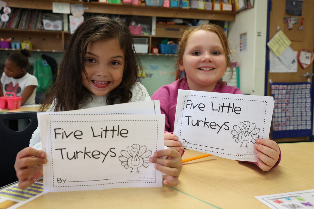students holding up five little turkeys workbooks