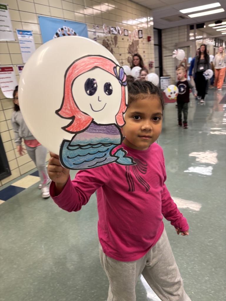 Students hold up balloons for a Macys day inspired school parade. Studnet holds up a mermaid balloon.
