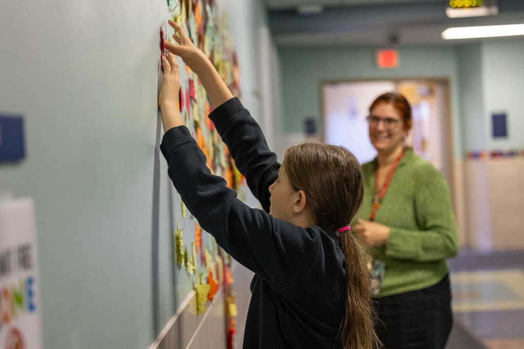 student hanging leaves on the wall