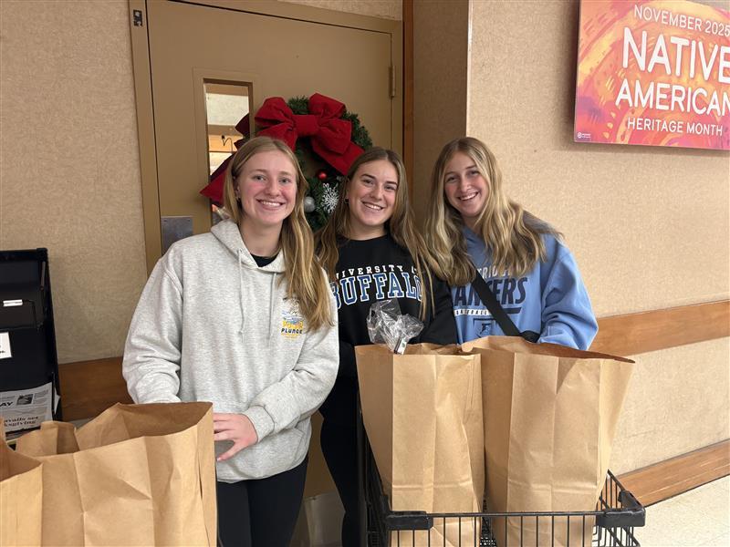 Girls volleyball team with paper bag groceries smiling with carts