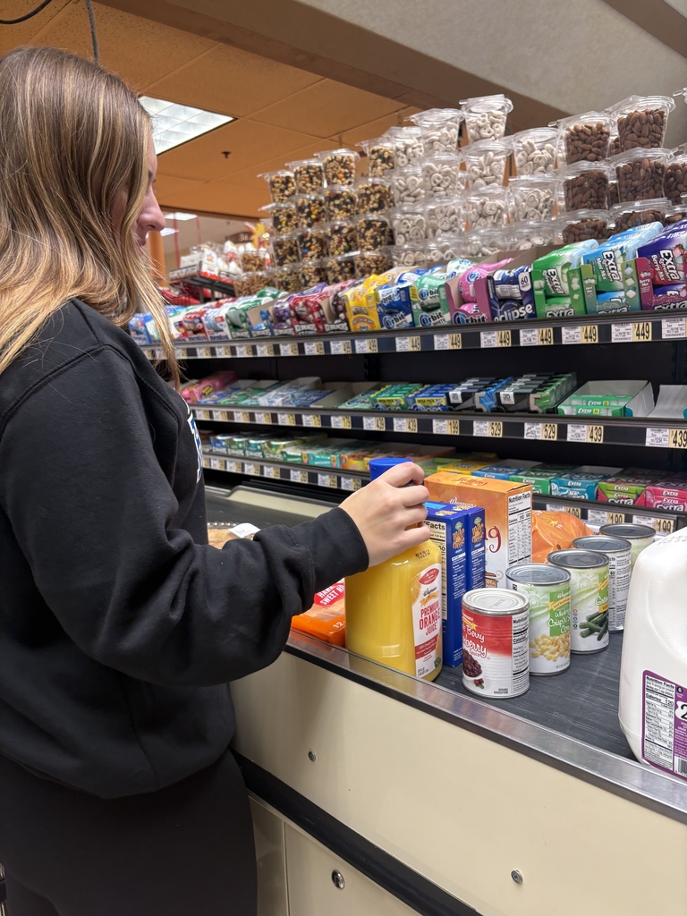 student puts groceries on the belt in the check out line