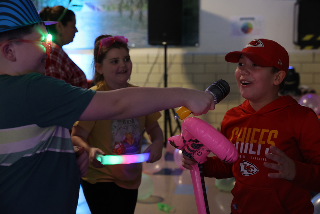 students hold mic up to friend while he smiles