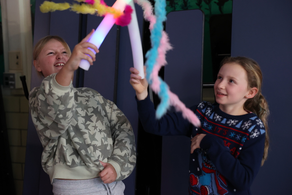students hold up glow sticks and boas