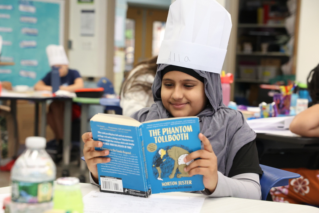 student smiles and looks at the phantom tollbooth book