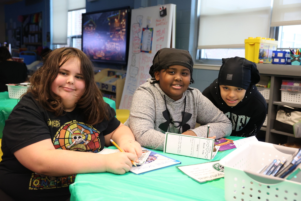 Students smile while sitting at a library table