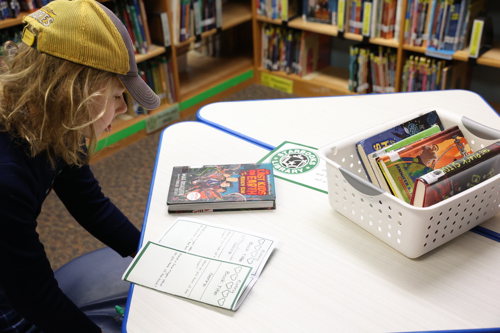 student examines book with worksheet