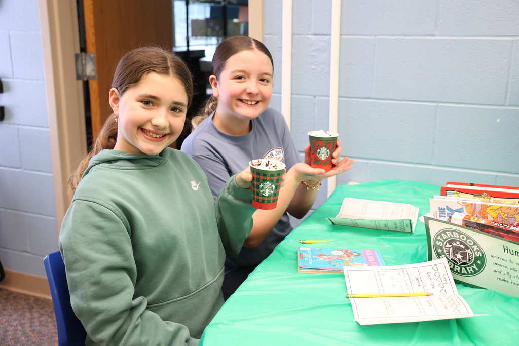 students smile while holding up hot cocoa cups