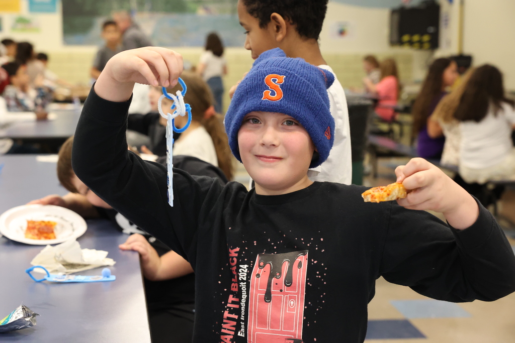 student holds up pizza and book mark
