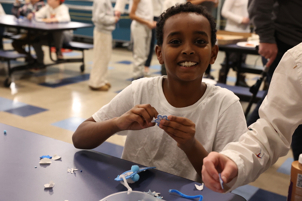 student smiles while making craft 
