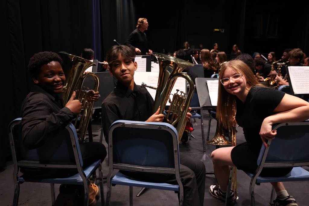 Students turn and pose in chairs with instruments 