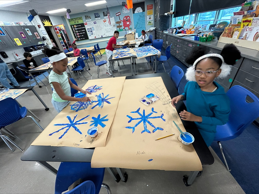 students paint blue snowflakes on a large piece of paper 