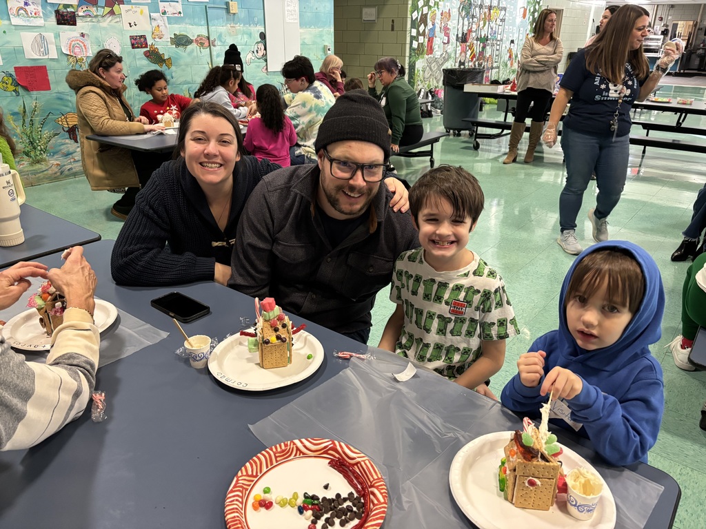 family poses with kids while making gingerbread house