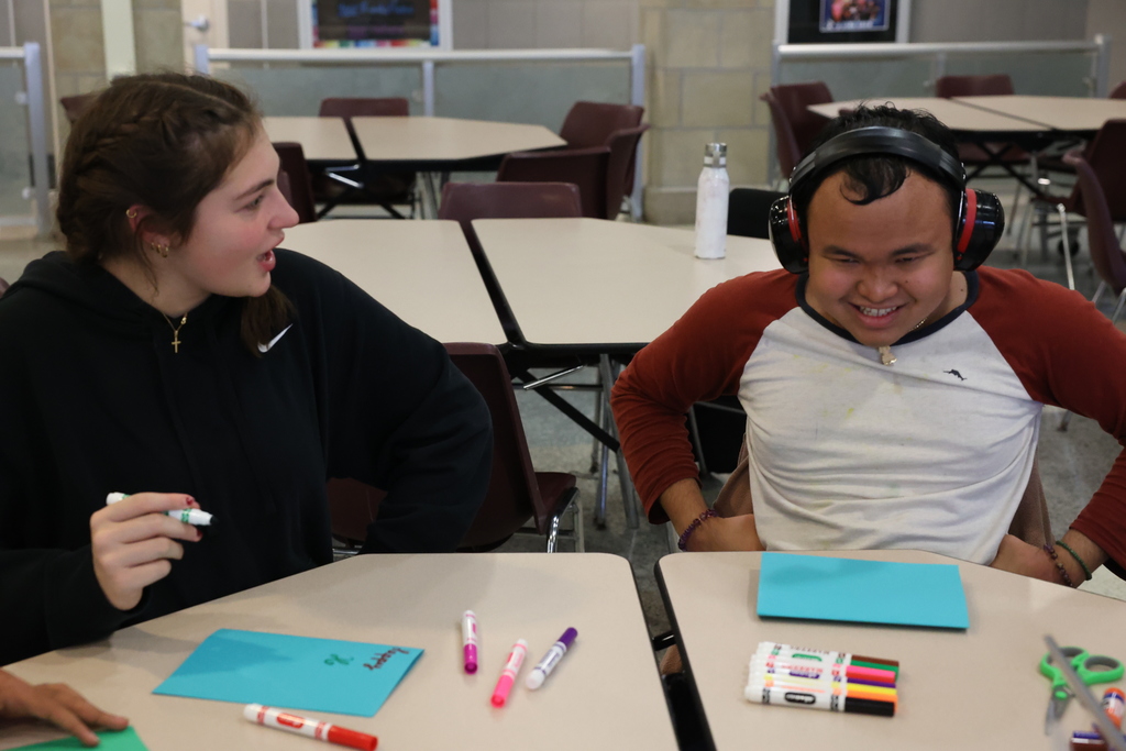 students laugh while making cards with hands on hips 