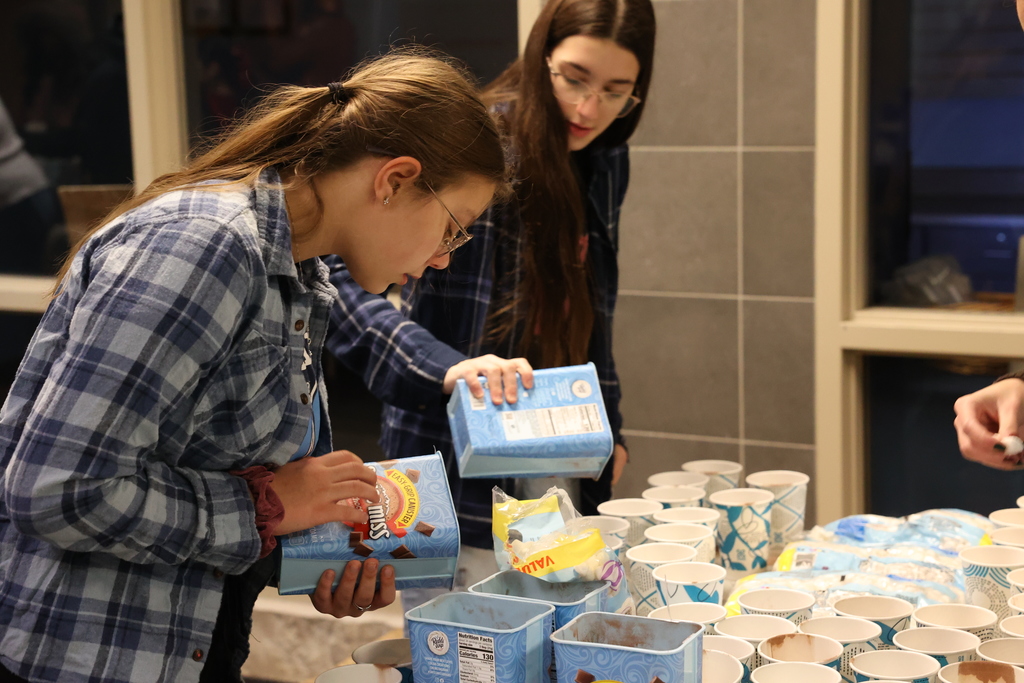 Students pour hot cocoa mix into cups