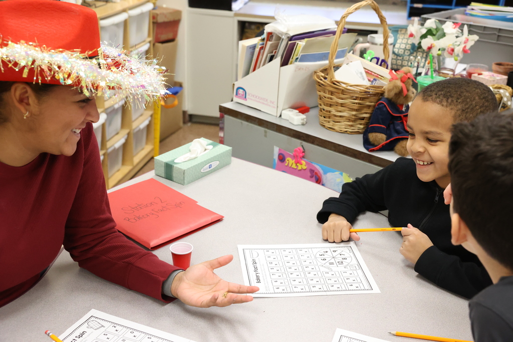 student smiles while working on worksheet with a teacher