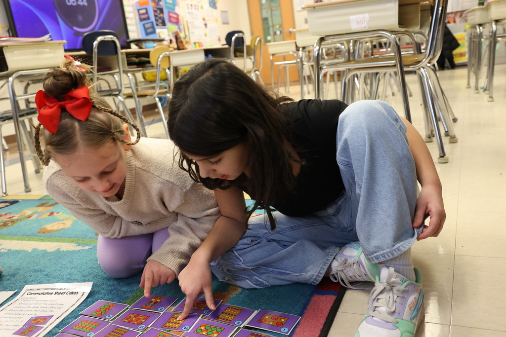 Students point at cards on the floor