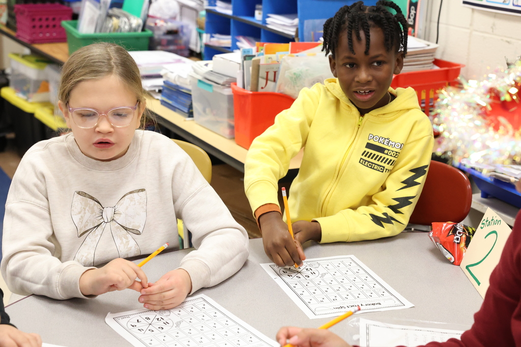 Students sit at table working on worksheet