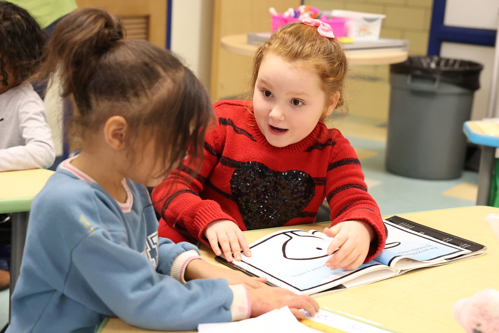 student reads book to other student