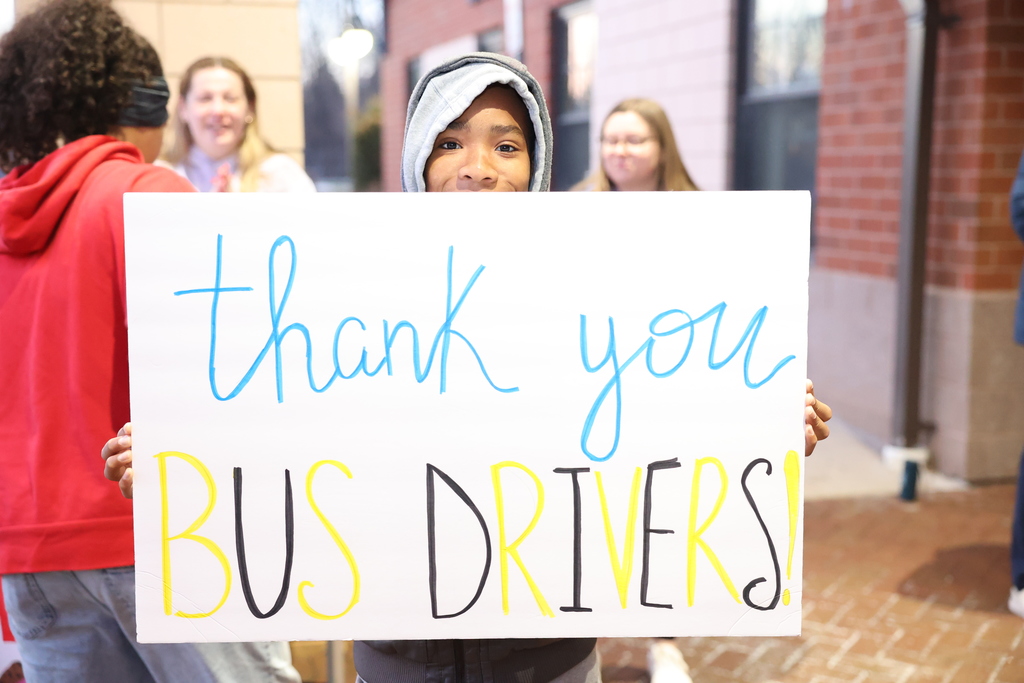 student holds up thank you bus drivers sign