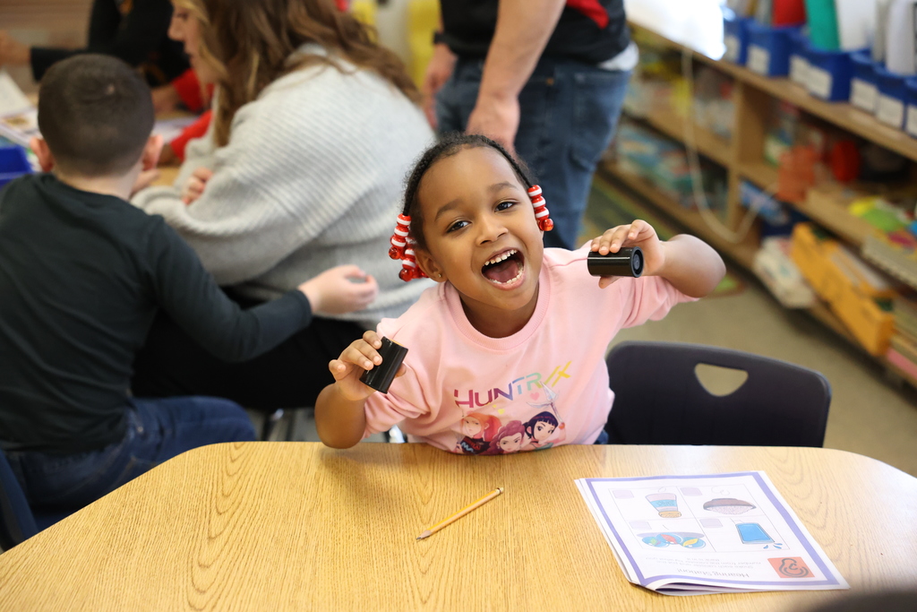 Student smiles and shakes film canisters 