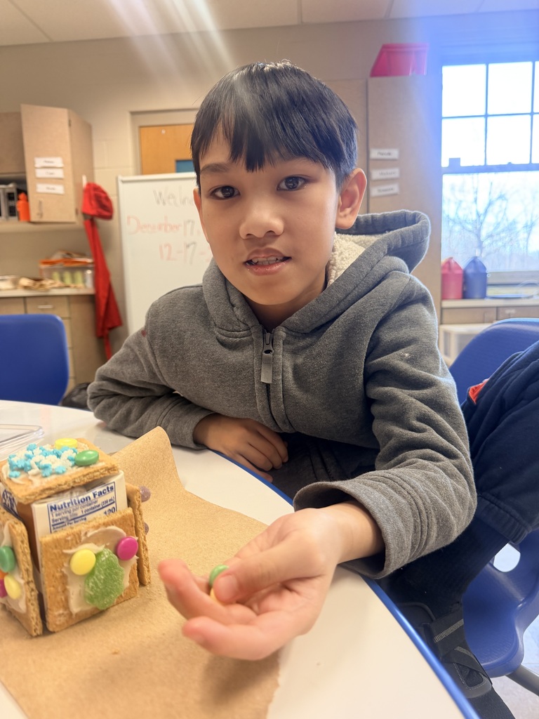 student smiles while making gingerbread house