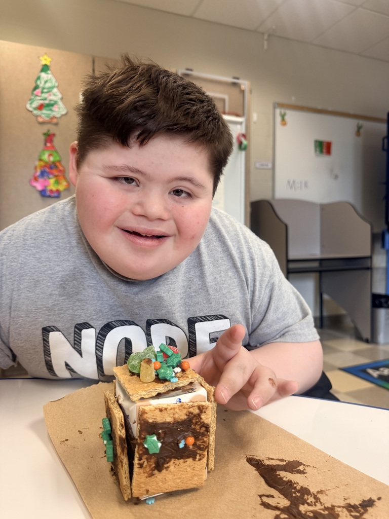 student smiles with gingerbread house