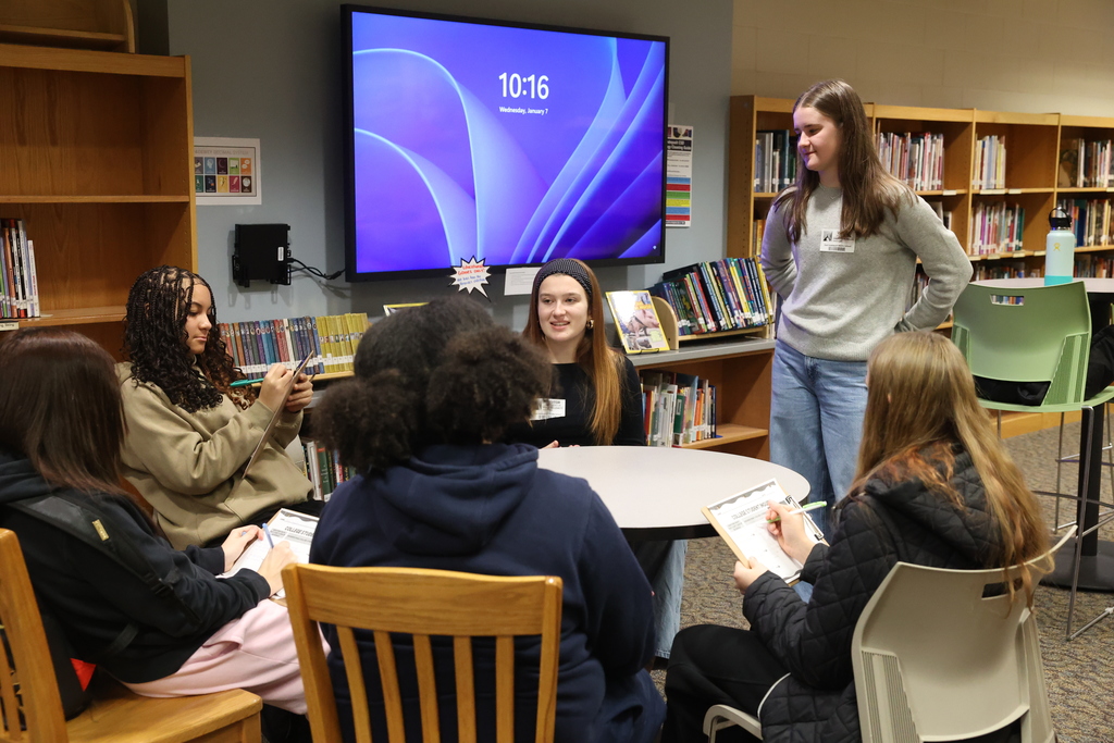 students sit around a table discussing college life with visitors