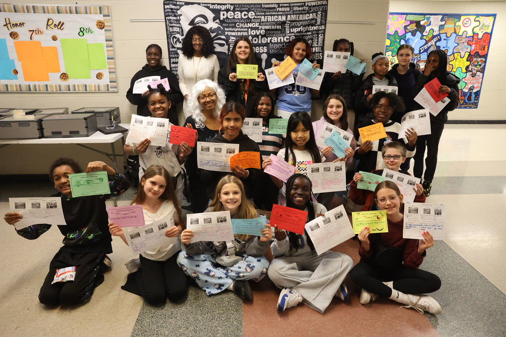 Students hold up worksheet and signs about what they can do to make the world a better place 