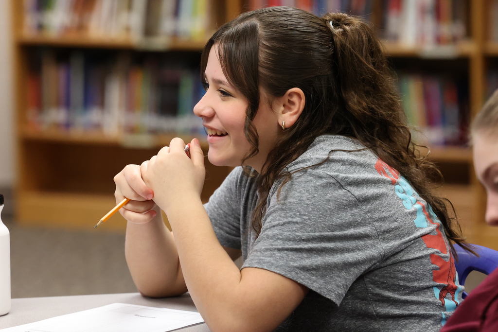 student smiles while holding pencil