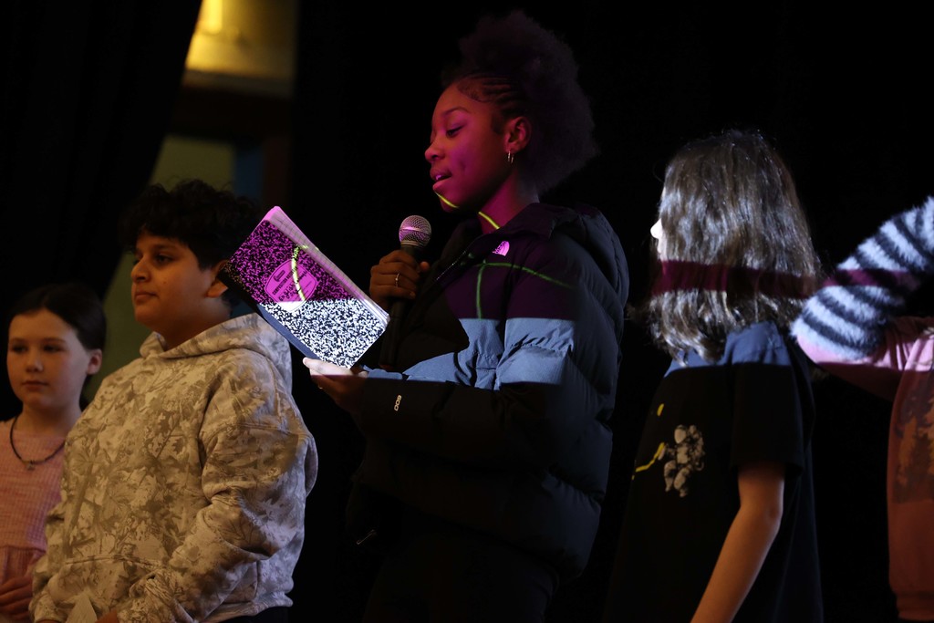 students read on stage with mic
