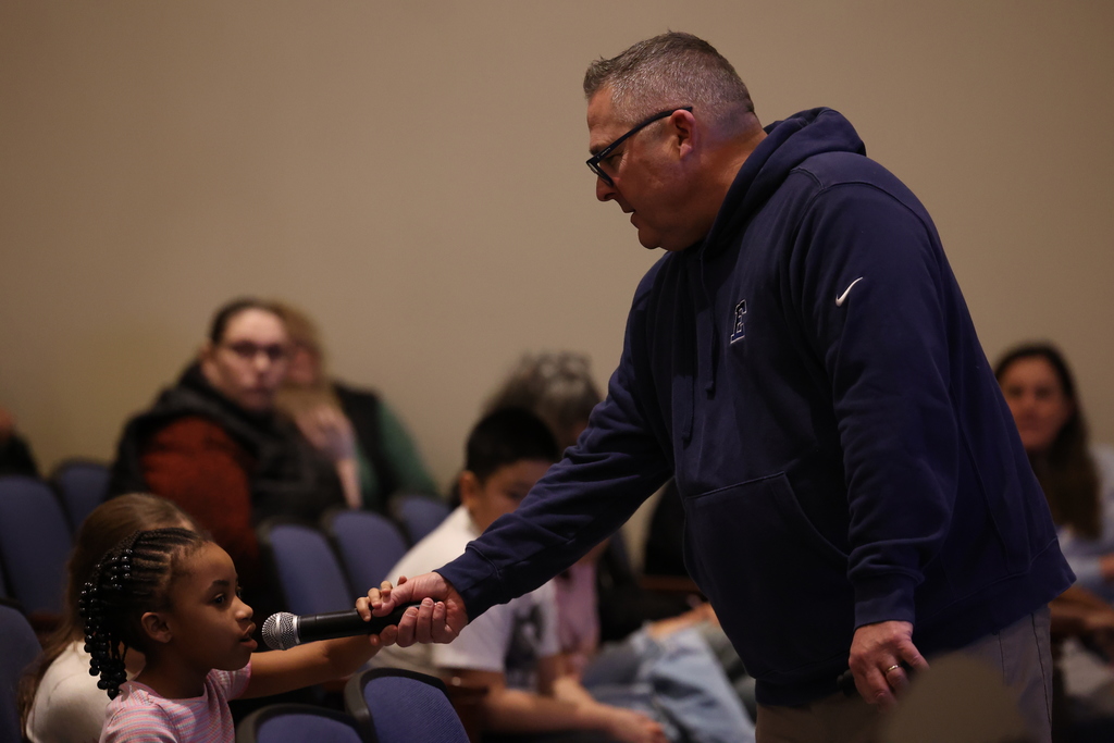 principal holds mic up to student in audience
