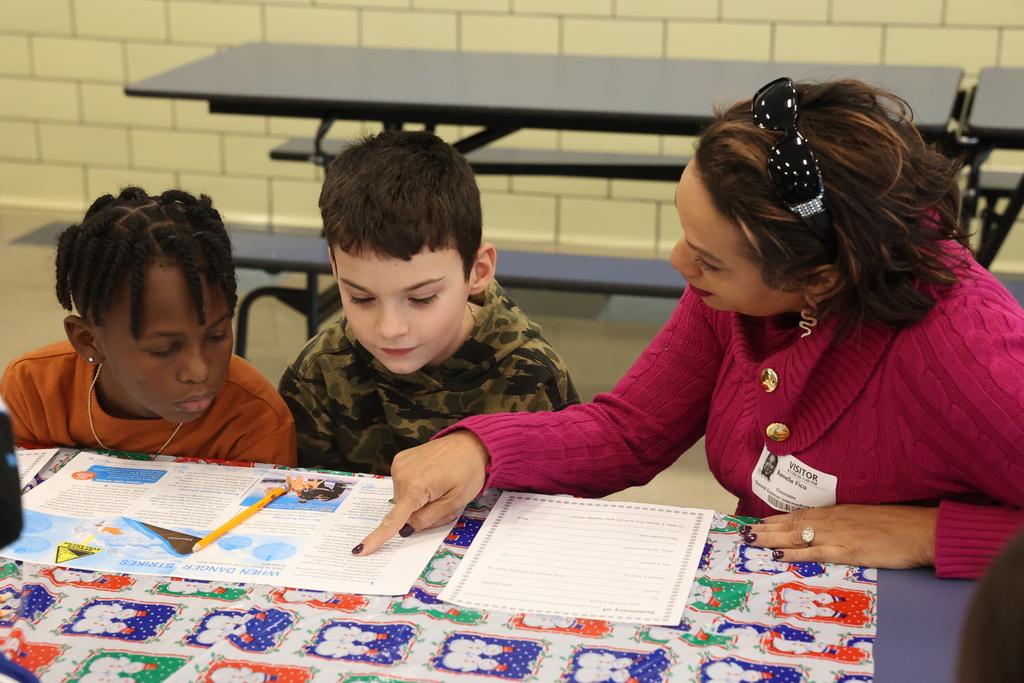 school visitor points to article where she reads with two students