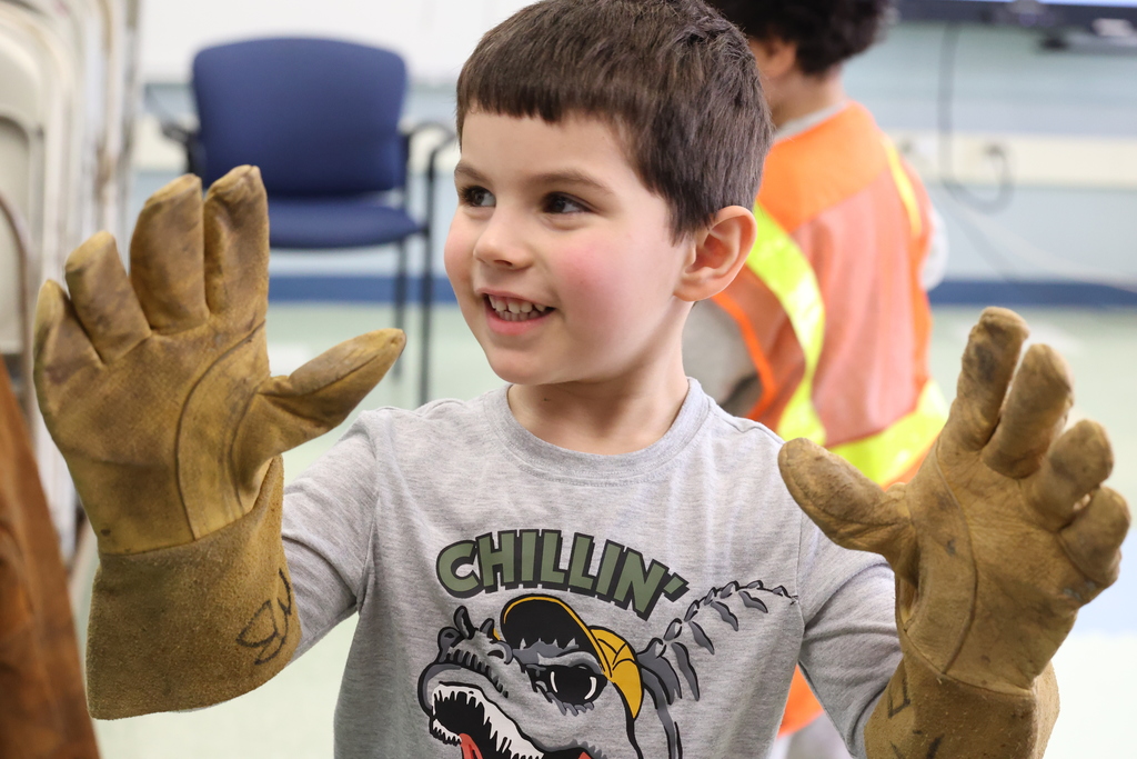 student smiles wearing large gloves
