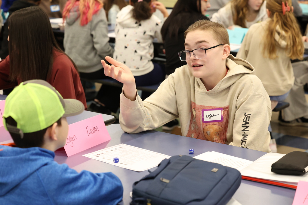 high school students talks to elementary student at a table