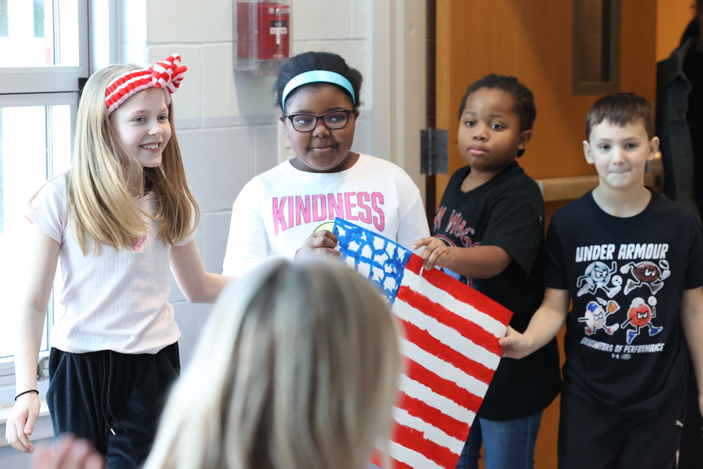 students hold up american flag and smile 