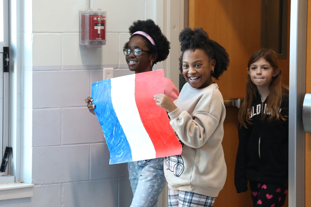 students hold up French flag and smile 